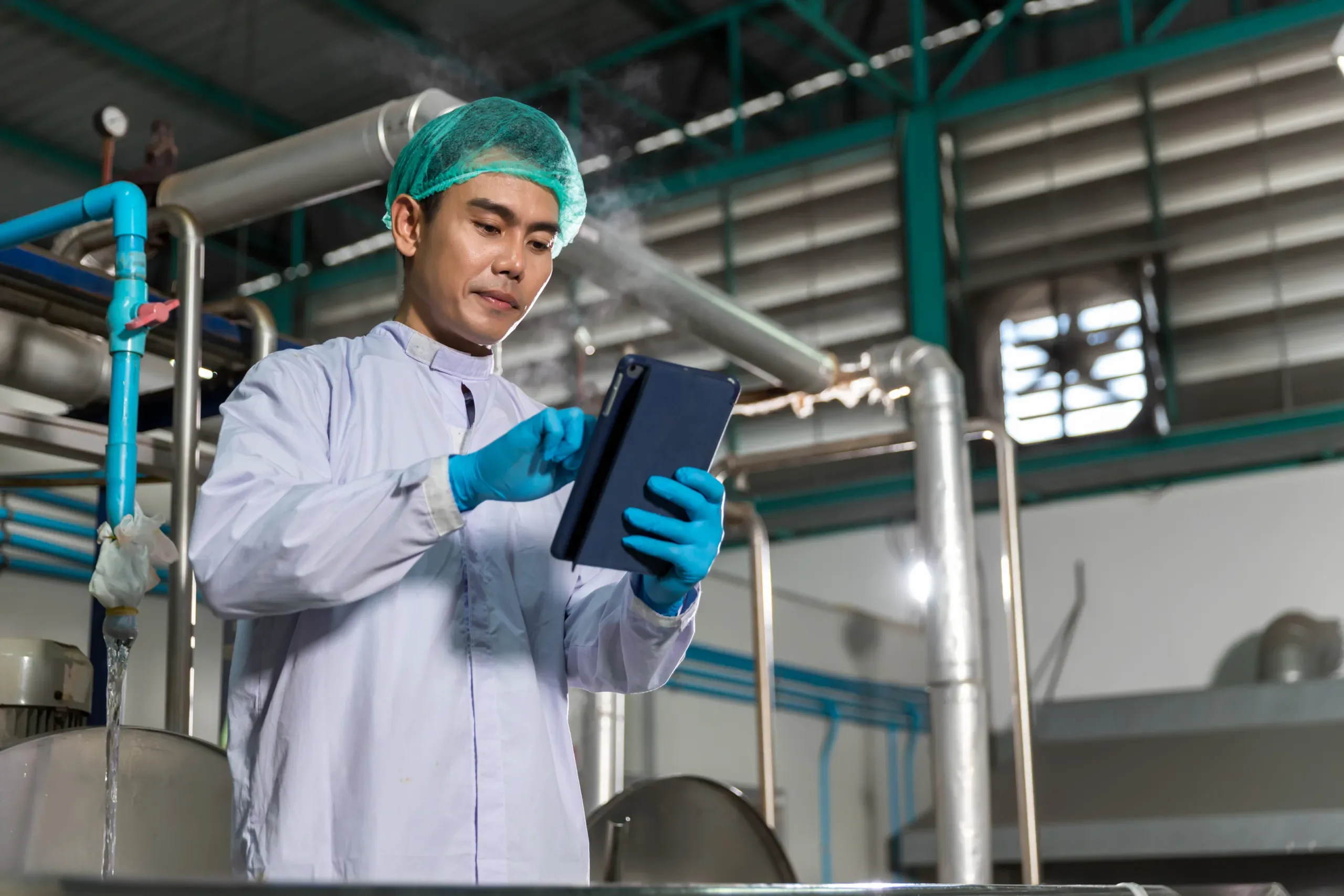 Worker in a manufacturing environment, analyzing efficiency data on a tablet.