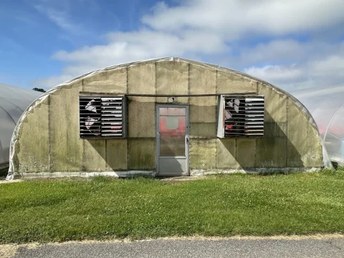 Exterior view of the fan end of the X.S. Smith Quonset greenhouse labeled GH11 at White's Greenhouse Auction on SecondBloom Auctions platform, featuring essential fan equipment.