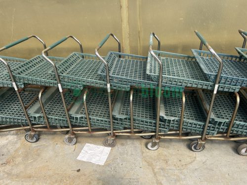 Multiple used two-level nursery shopping carts joined together, each with green hard plastic shelves featuring square holes.