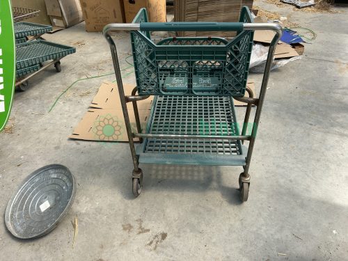 Rear view of a used two-level nursery shopping cart, displaying the sturdy construction and spacious shelves.