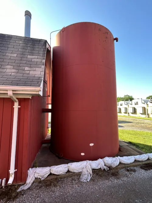 Large red industrial storage tank situated near the side of a shed.