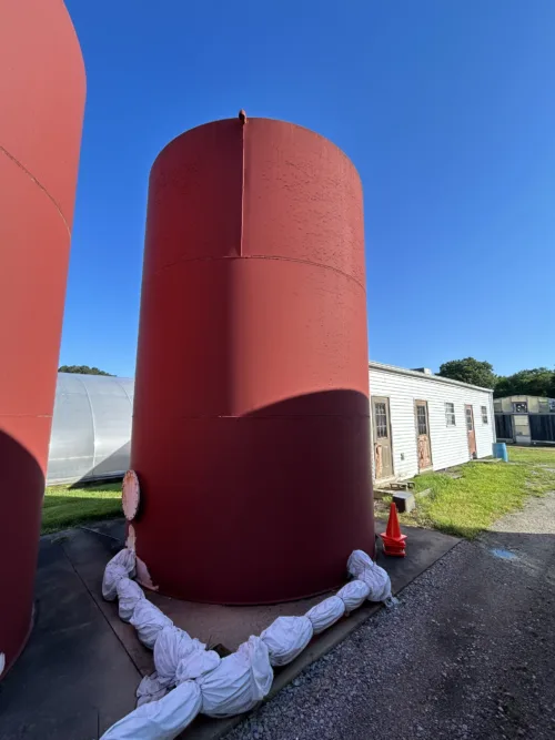 A single large red industrial-grade storage tank standing outdoors.