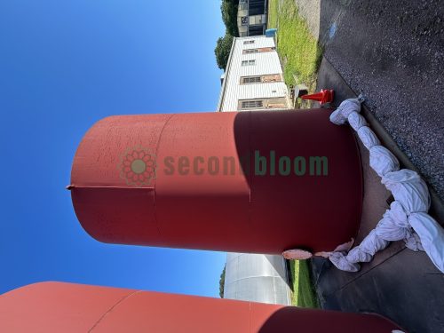 A single large red industrial-grade storage tank standing outdoors.
