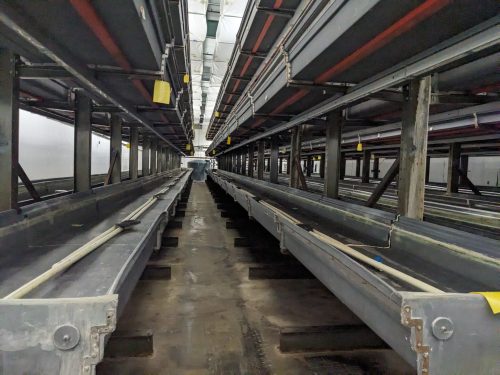 A detailed view of a vertical farm system installed at Your Local Greens in Burlington, North Carolina, featuring multi-level growing trays previously part of the FarmedHere system in Bedford Park, IL.