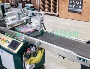 A Bouldin & Lawson machine in a production facility with trays on the conveyor belt.