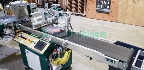 A Bouldin & Lawson machine in a production facility with trays on the conveyor belt.