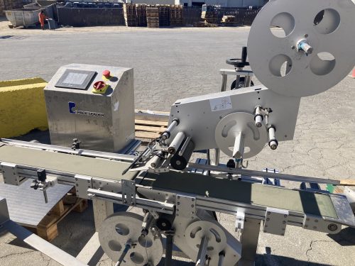 Close-up view of a Pack Leader PL-221 labeling machine, used in leafy greens packaging, showcasing conveyor belt, labeling mechanism, and control panel near Gonzales, California.