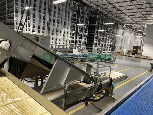 A Hamill microgreens harvester with stainless steel conveyors, operating inside a climate-controlled vertical farming facility for efficient and sustainable indoor crop production.