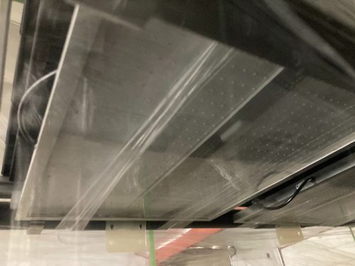 Close-up view of wrapped growing trays showing horizontal shelf configuration through plastic