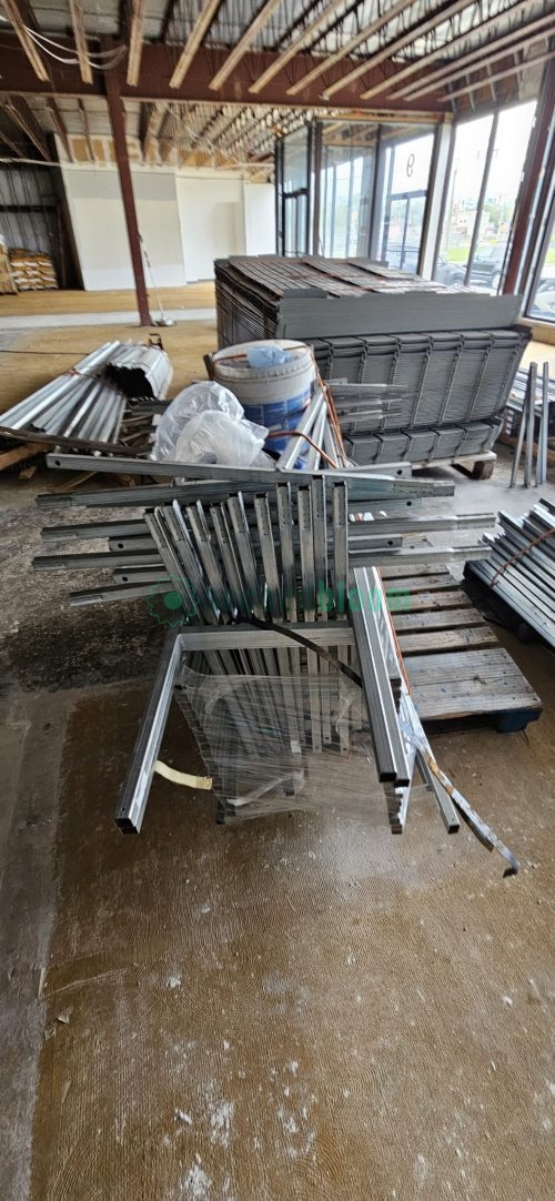 Overhead view of stacked aluminum and galvanized steel components for greenhouse benches showing different shapes and sizes