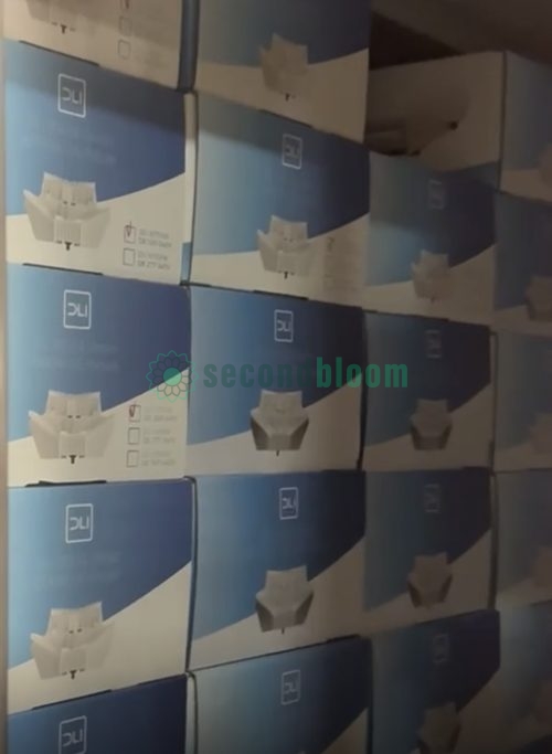 Close-up view of stacked DLI grow light boxes showing product packaging and branding in warehouse