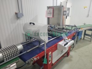 Commercial seeding equipment with perforated metal drum, conveyor system and control panel in vertical farming facility