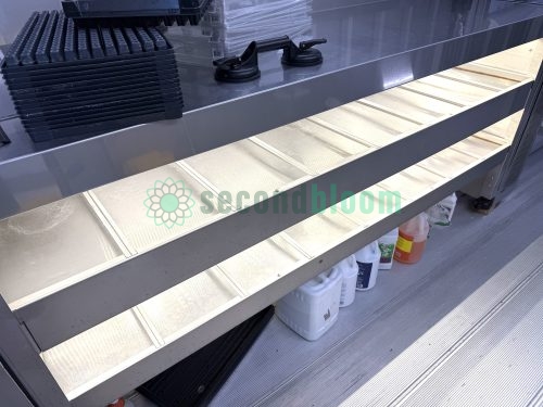 Close-up of white LED light panels illuminating hydroponic growing channels in container farm