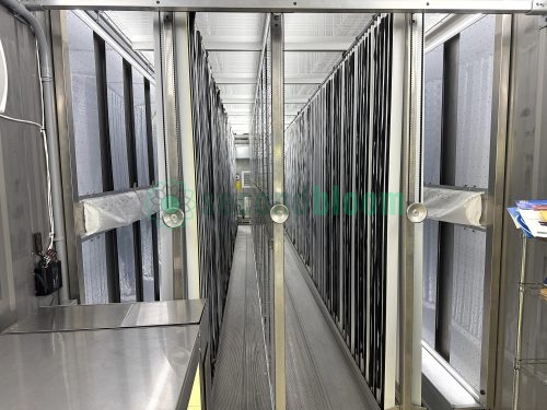 Symmetrical view down center aisle of container farm showing vertical growing towers on both sides