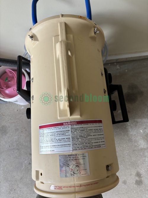 Cream-colored chemical tank showing warning labels and calibration information